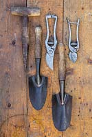 Collection d'outils de jardin vintage sur une surface en bois. Sécateur, dibber de semence et truelles à main