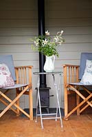 Chaises en bois et poêle à bois dans Shepherds Hut avec des fleurs de printemps en pot