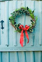 Décorations de Noël de votre jardin - couronne faite de branches choisies de conifères et de capitules suspendus à une porte peinte
