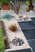 Jardin de gravier terminé avec pavage de calcaire noir et plantes en été.