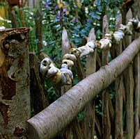 Clôture en bois inhabituelle sur le thème de la mer, filetée avec une chaîne de pierres hagstones - cailloux lavés à la mer naturellement avec trou au milieu