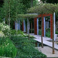 Des paravents en bois rouge et gris divisent le jardin moderne. Passerelle de granit passe des piscines et des parterres d'iris, de lys martagon, de fougère, d'hosta, de digitale, de bouleau.