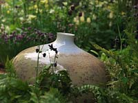 Reposant dans un parterre de fleurs herbacées, joli pot à glaçure cristalline par le potier John Stroomer.