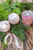 Décorations de Noël sur le thème de la couleur champagne. Boules, ruban, porte-bougie chauffe-plat, feuillage d'aulne et d'if