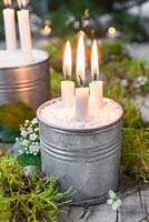 Bougies montées dans des boîtes métalliques contenant du sel, décorées de mousse et de Crataegus - Fleur d'aubépine.