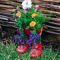 Paire de bottes Wellington pour enfants utilisées comme cache-pot amusant, plantées de lobelia, de souci français, de pétunia et de brachyscome.
