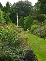 Jardin cadran solaire. Mélange de conifères, herbacé tendre dans des haies d'ifs élevés. Usine d'huile de ricin, Paulownia, canna, Dicksonia antaractica, salvia, dahlia, Verbena bonariensis, agapanthus, tithonia.