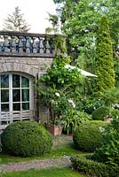 Vue de la maison et du jardin avec parterres de fleurs, arbres matures et box topiaire. Marina Wust, Allemagne