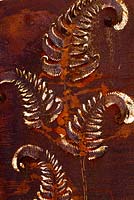 Panneau en métal rouillé orné de feuilles de fougère fournissant un point focal. Au Domaine de Cambou, Verfeil, Haute-Garonne, Midi Pyrénées, France.