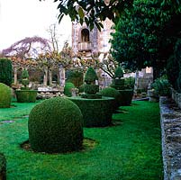 Des formes topiaires en boîte clippée défilent sur la pelouse menant à la maison des Arts et Métiers flanquée de creux en pierre et d'une avenue de chaux.