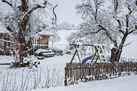 Scène d'hiver avec piquet de grève en bois, équipement de jeu pour enfants, arbres et cabanon