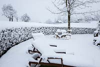 Aspect hivernal avec salon de jardin enneigé, haie et vue sur le paysage, Cornus mas