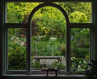 La vue depuis la fenêtre de la cuisine encadre un vieux pommier, vu à travers les parterres d'Iris, d'Aquilégie, d'Allium et de Valériane,