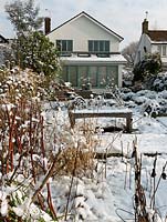Vue de la maison dans un jardin de la Tamise conçu par Andy Sturgeon. Coffret topiaire, herbes et plantes architecturales couvertes de neige.