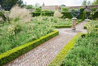 Les plates-bandes bordées de fleurs dans le jardin clos contiennent un mélange d'achillea, verbascum et Stipa gigantea, avec cadran solaire au centre. Beaminster Manor, Beaminster, Dorset, Royaume-Uni