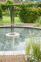 Piscine circulaire avec élément d'eau dans le jardin clos conçu par Lesley Cooper, avec Erigeron karvinskianus et dierama autour du bord. Beaminster Manor, Beaminster, Dorset, Royaume-Uni