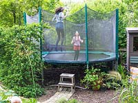 Isla et Romy rebondissent sur le trampoline filtré dans un jardin familial, Muswell Hill, Londres.
