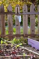 Fourchette à main et truelle accrochée à une clôture à côté des parterres de légumes.