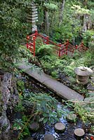 Pont de pierre traversant l'étang avec des pierres de gué rondes au jardin tropical de Monte Palace, Madère, dans le jardin oriental, avec des objets japonais et des balustrades rouge vif