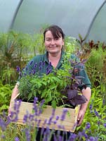 Anne Marie Owens, jardinière en chef au Manoir, avec une boîte d'herbes fraîches et de fleurs cultivées dans le potager.