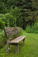Ancien banc en bois sur pelouse verte dans un jardin privé en été