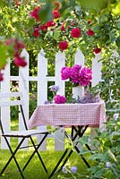 Arrangement de fleurs coupées avec pot de pivoine sur table de jardin en été. Rosa 'Crimson Glory' - rosier grimpant