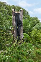 Le jardin Laurent-Perrier Chatsworth. Sculpture de tronc d'arbre brûlé, cardères, chêne anglais, tulipes et merle en lambeaux.