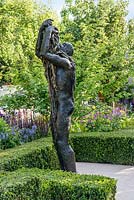 Le jardin Morgan Stanley Healthy Cities. Sculpture en bronze d'une figure avec boîte de couverture et parterres de fleurs herbacées en arrière-plan
