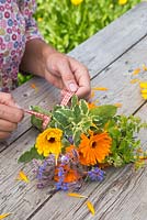 Femme créant un bouquet floral de Calendula officinalis 'Art Shades', sauge et bourrache