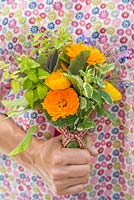 Femme tenant un bouquet floral de Calendula officinalis 'Art Shades', sauge et bourrache