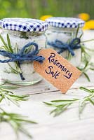 Sel de romarin fait maison, à base de sel marin et de feuilles de Rosmarinus officinalis, mis dans des bocaux en verre étiquetés, attachés avec de la ficelle