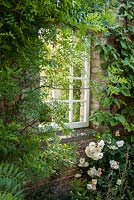 Fenêtre décorative dans un mur de jardin encadré de Xanthocerus sorbifolium