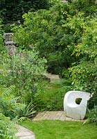Surplombant le jardin pour asseoir sculpté par l'olivier. Les plantes comprennent Sumach, Olea Europaea, Thalictrum et Alliums au loin. Chaise de jardin en béton moulé par Solid Soul Furniture Designs.