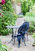 La terrasse du petit déjeuner avec assise et chaises peintes en bleu. Rosa Tess of the D ' Urbevilles ', Ausmove PBR on wall. Orchard House, Sedbury, Gloucestershire. Jardin conçu et créé par Stella Caws. Juin 2015.