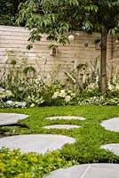 Paysages vivants 'City Twitchers' - vue montrant les zones pavées circulaires, la pelouse de camomille, les nichoirs, le prunier et la plantation mixte de blanc - RHS Hampton Court Flower Show 2015