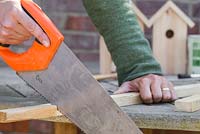 Utilisez une règle et mesurez le toit du nichoir, en sciant des bâtons en bois pour correspondre aux longueurs requises
