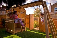 Fille sur balançoire. Aire de jeux pour enfants avec cadre d'escalade en bois. Petit jardin urbain contemporain urbain. Jardin Ansari, Harrow