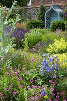 Tonnelle bleue et plates-bandes herbacées, y compris géraniums, campanules et achemilla mollis