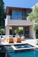 Vue sur la piscine moderne et la maison avec des chaises longues et un olivier mature.