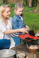 Enfant plantant une brouette jouet avec des plantes succulentes. Remplissez la brouette de compost.