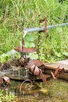 Plan d'eau composé de fleurs de nénuphars et de coussinets en terrasses d'acier rouillé, provoquant une cascade d'eau vers l'étang. Jardin des Cimes Chamonix, juillet