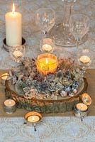 Décoration de table festive allumée à la bougie en allium séché, roses, échinops, houx de mer, hortensia, statice et têtes de graines de coneflowers, coquelicots et nigella.