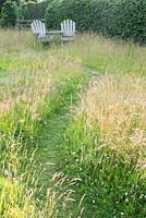 Chemin tondu dans les hautes herbes avec des chaises Adirondack