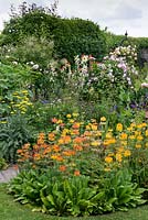 Un jardin de chalet avec parterre de fleurs mélangé coloré de candélabres primula, achillea, nepeta, aquilegia, flaf iris, roses 'Fantin Latour'