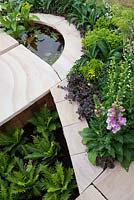 Parterre de jardin en grès coulé avec des bords incurvés et un élément d'eau semi-circulaire.