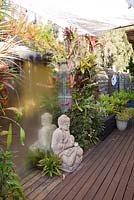 Vue du platelage en bois montrant les murs végétaux de diverses broméliacées et tillandsias avec Bouddha assis devant un miroir trompe l ' oeil