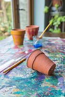 Les matériaux requis sont une règle, un crayon, des pots en terre cuite, un pinceau et de la peinture