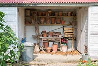 Bâtiments de stockage de jardin avec de vieux pots de fleurs sur des étagères.