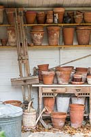 Bâtiments de stockage de jardin avec de vieux pots de fleurs sur des étagères.