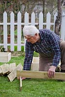 Homme construisant un bac à compost.